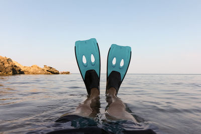 Low section of man in sea against clear sky