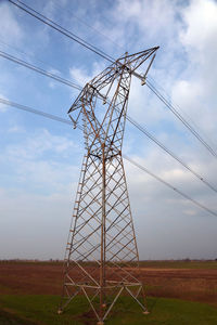 Low angle view of electricity pylon on field against sky