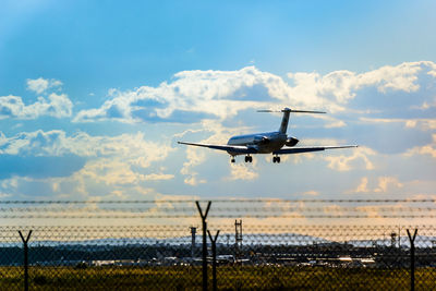 Low angle view of airplane landing at runway against sky