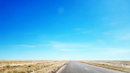 Road leading towards blue sky