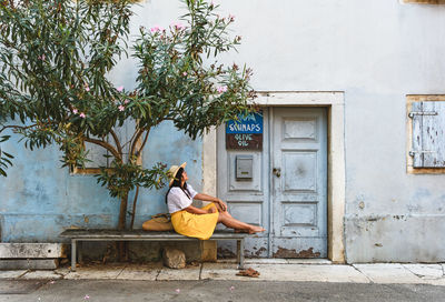 Woman sitting on seat against building