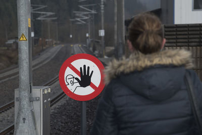 Rear view of woman with arrow sign on road