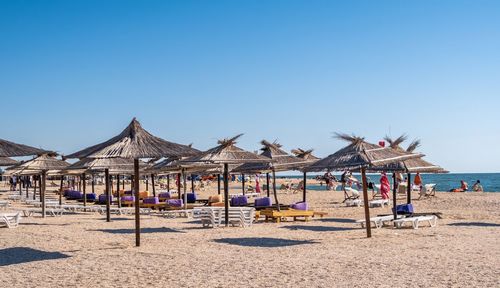 Traditional windmill on beach against clear blue sky