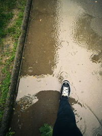 Low section of person standing on wet floor during rainy season