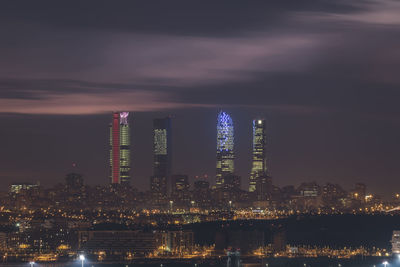 Illuminated modern buildings against sky at night