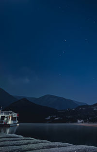 Scenic view of lake against mountains at night