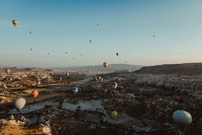 Hot air balloons flying over land against sky