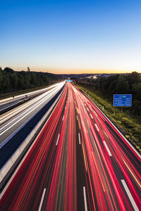 High angle view of light trails on highway against blue sky