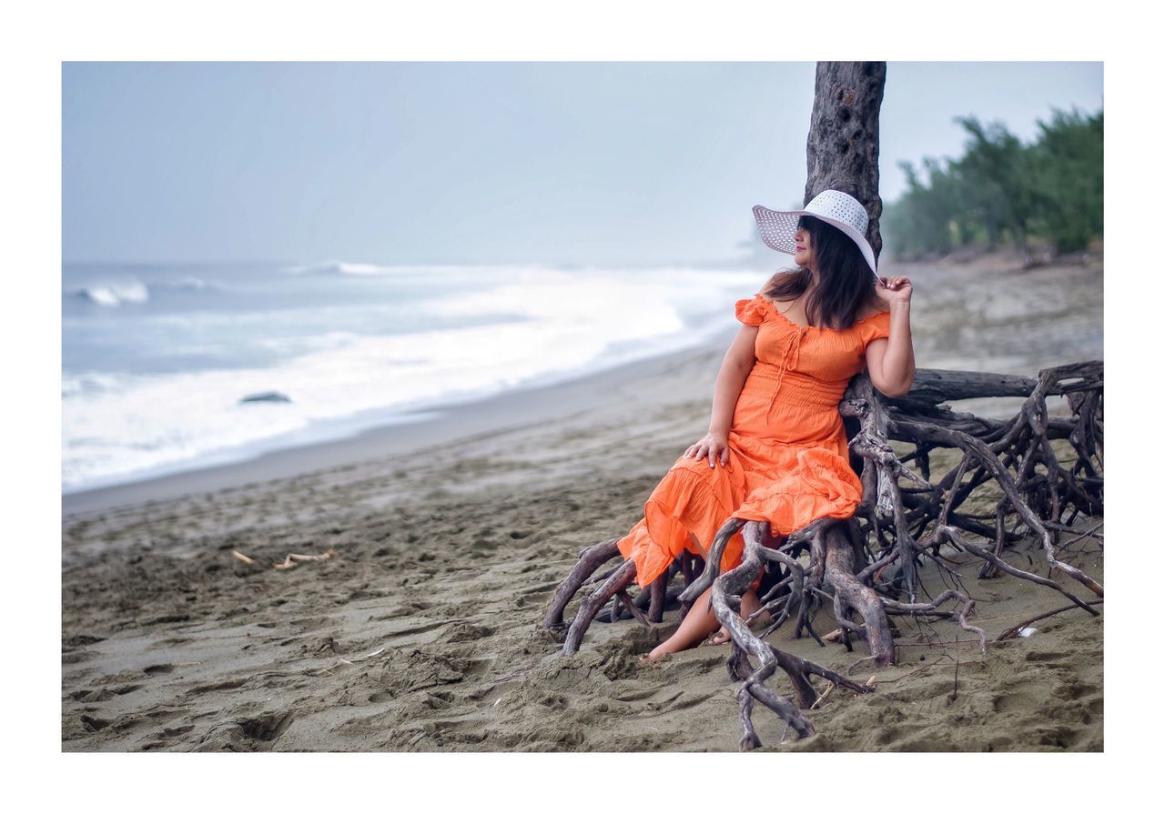 YOUNG WOMAN LOOKING AT BEACH