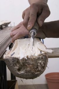 Close-up of craftsperson using tool on wood at workshop