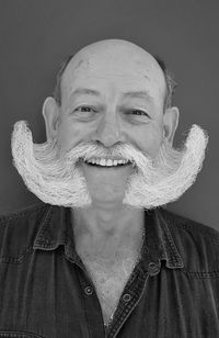 Close-up portrait of bearded man smiling against gray background