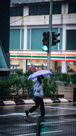 Rear view of man walking on street during rainy season