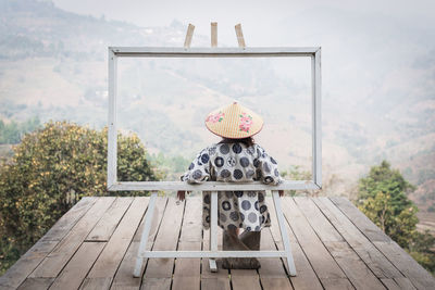 Lady with yukata shirt and bamboo hat in the frame against mountain scenic view