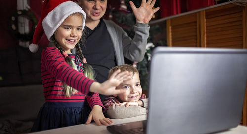Safe online christmas. happy family in santa red hats celebrating virtually via internet