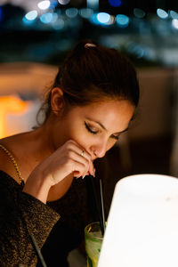 Portrait of a young woman drinking from glass at restaurant