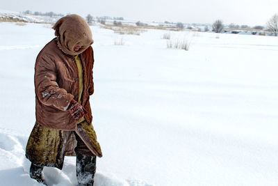 Rear view of man walking on snow field