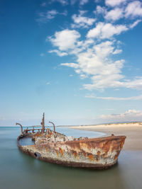 Abandoned boat on sea against sky
