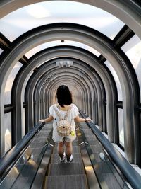 Rear view of woman standing on escalator