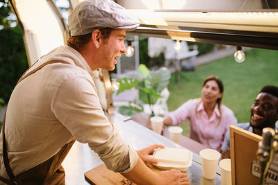 Side view of man using digital tablet while sitting on table