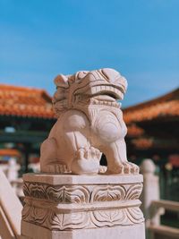 Close-up of statue against building against sky