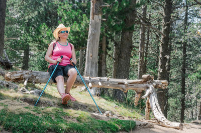 Full length of young woman amidst trees in forest