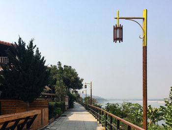 Street by footbridge against sky
