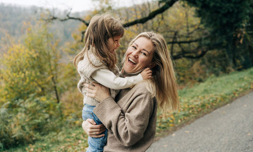 Portrait of smiling young woman standing against trees