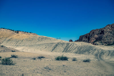 Scenic view of desert against clear blue sky