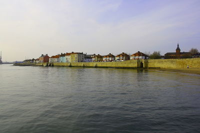 Scenic view of river by buildings against sky