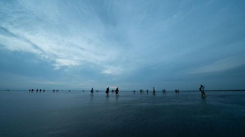 People on beach during sunset against sky