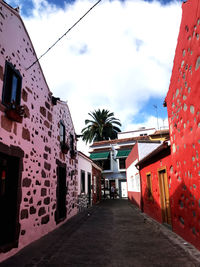 Alley amidst buildings in city against sky