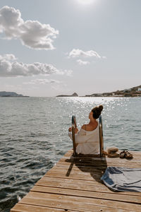 Rear view of woman sitting by lake