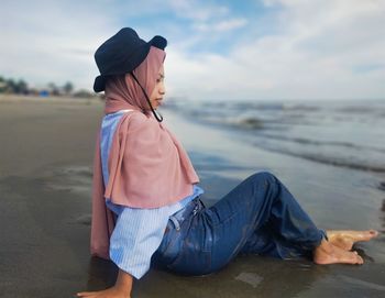 Rear view of young woman sitting on beach