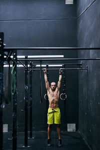 Shirtless fit young man working out in a cage at indoors gym