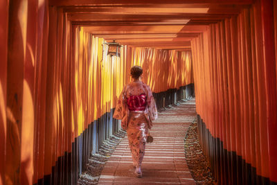 Rear view of woman walking on footpath amidst shrine