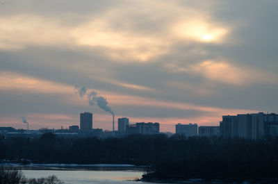 Smoke emitting from factory against sky during sunset