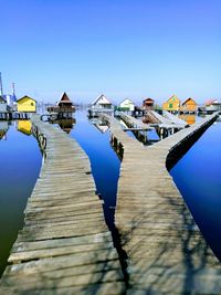 Wooden pier over sea against clear blue sky