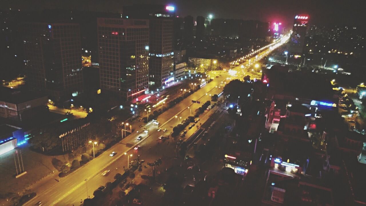 illuminated, night, city, transportation, building exterior, architecture, traffic, high angle view, built structure, road, street, car, city life, city street, land vehicle, street light, cityscape, mode of transport, light trail, long exposure