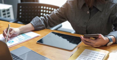 Midsection of man using mobile phone on table