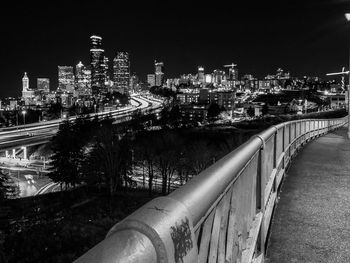 Illuminated bridge over river amidst buildings in city at night
