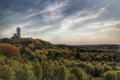 Trees on field against cloudy sky
