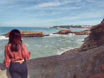 Rear view of woman looking at sea against sky