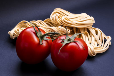 Realistic looking tomatoes and raw pasta isolated on blue background in brazil