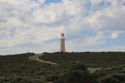 Lighthouse on street amidst buildings against sky