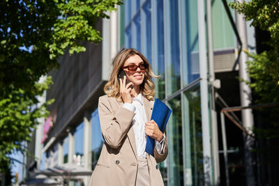 Portrait of young woman standing against building