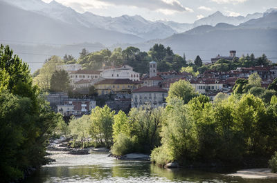 River amidst buildings and trees against mountains