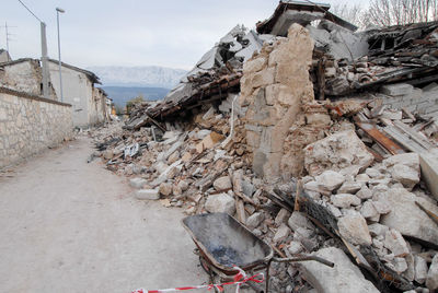 Abandoned house by wall against sky