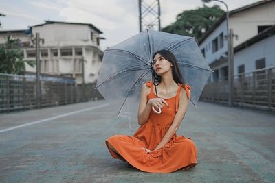Young woman holding umbrella while standing in rain