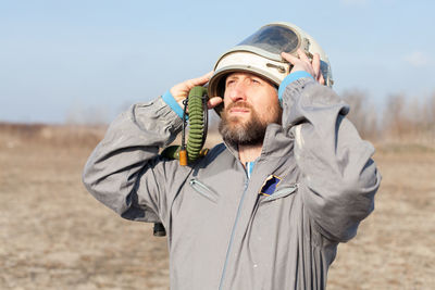Confident pilot wearing helmet while standing on field