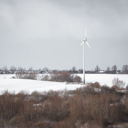 Windmill on field against sky during winter